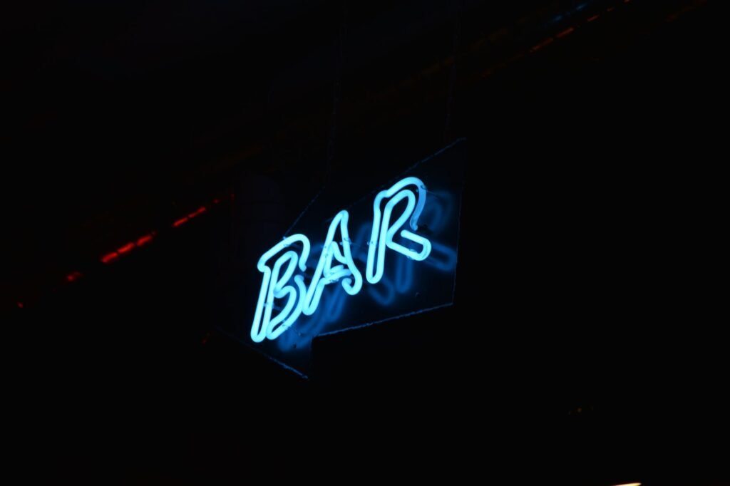 Glowing blue neon bar sign against a dark background, perfect for nightlife themes.