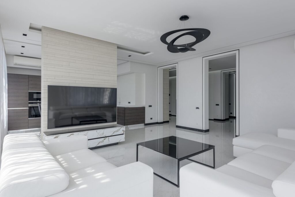 Modern bright house interior with table and sofa near TV with cabinet and white walls near entrance and lamp