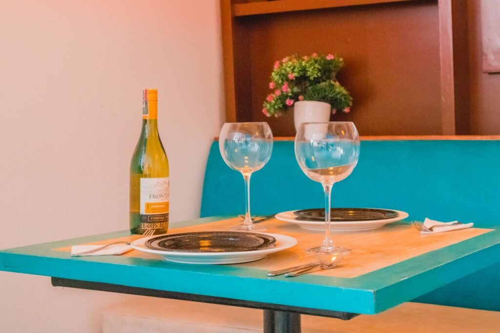 Charming dining setup with wine and glasses on a teal table, perfect for a romantic dinner.
