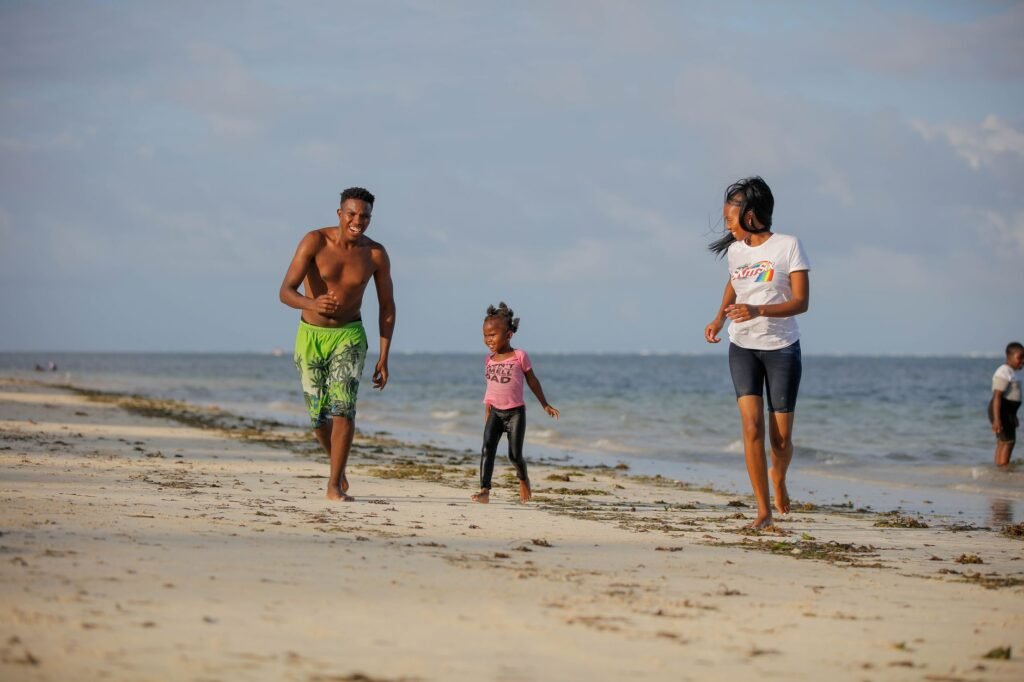 Happy family running and playing on a sunny beach day, creating joyful memories together.