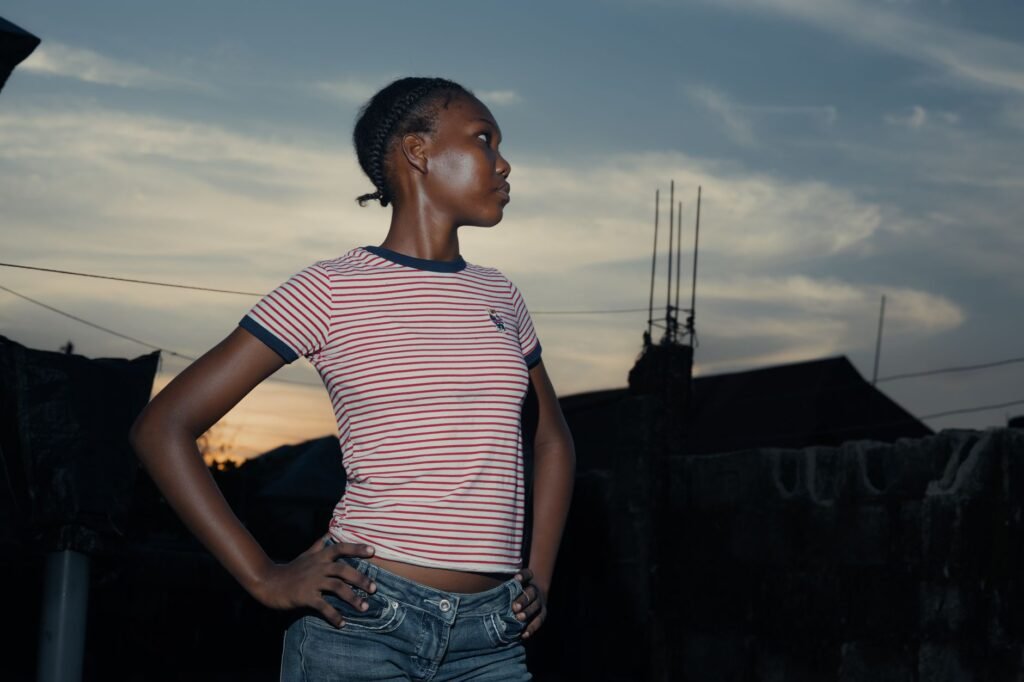 Portrait of a confident young woman standing outdoors at dusk, looking away.