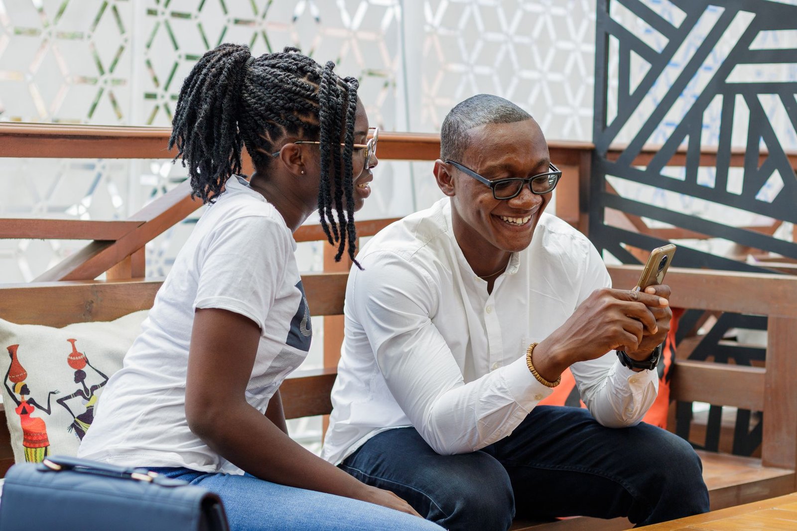 Smiling African couple sharing phone moments at a cafe in Accra, Ghana.