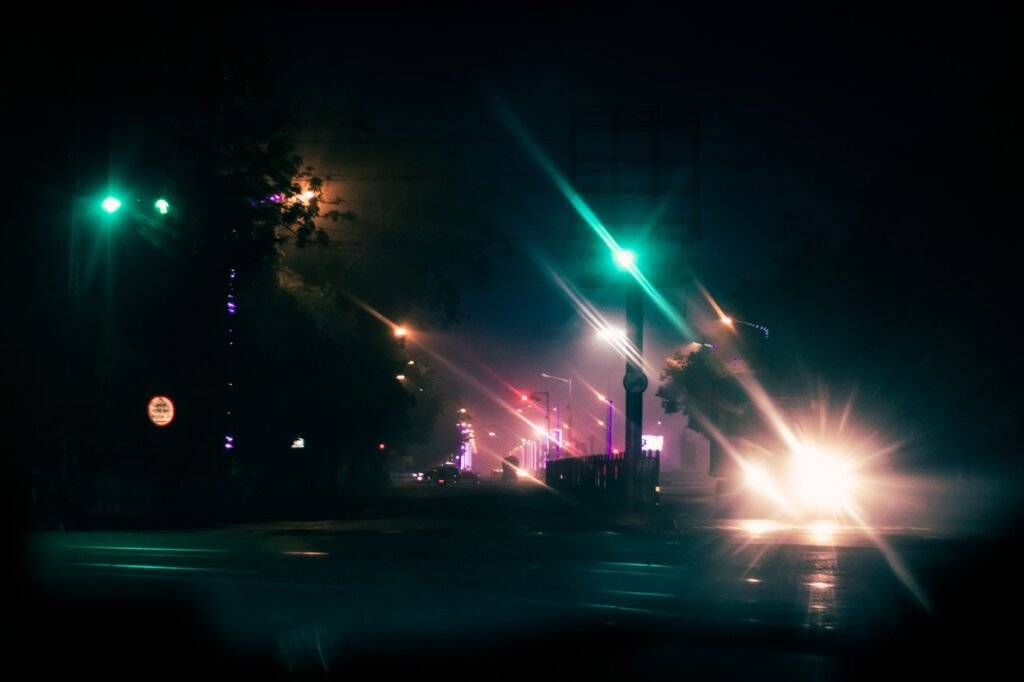 Bright light of car driving on empty night road and artificial light of lamps on streer