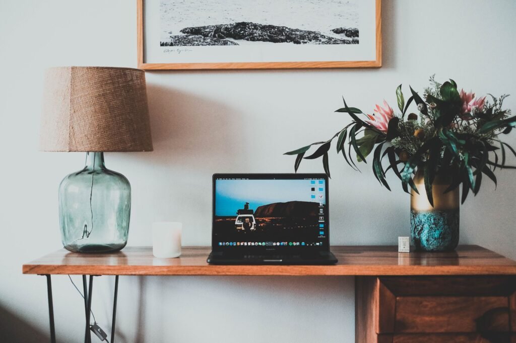 A well-organized workspace featuring a laptop, lamp, and decorative plants.