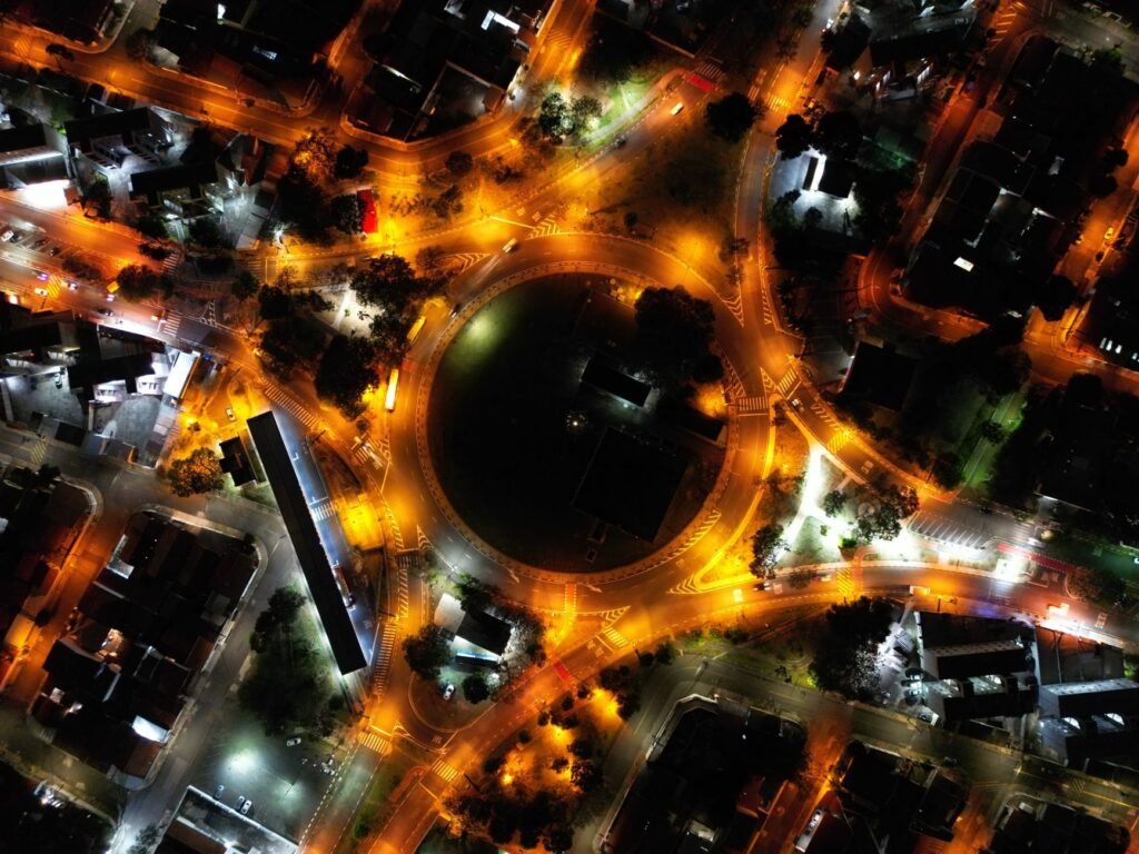 A stunning aerial view of a city roundabout lit up at night with vibrant streetlights and traffic.