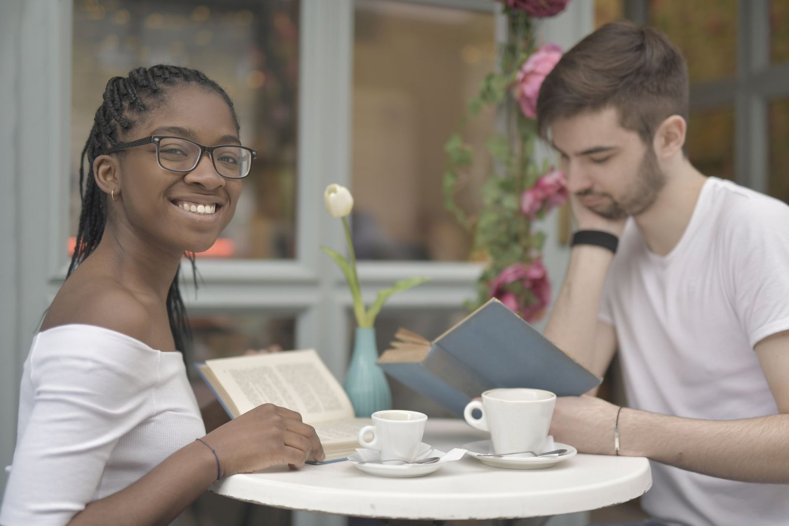 A couple enjoys coffee and books at an outdoor cafe, showcasing love and togetherness.