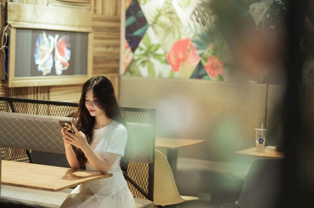 A young woman sits in a cozy Lạng Sơn cafe, engrossed in her smartphone.
