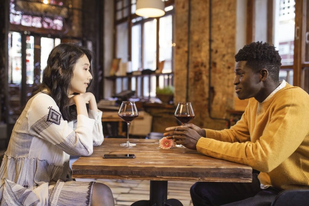 A couple enjoying a romantic date in a cozy café with wine and engaging conversation.