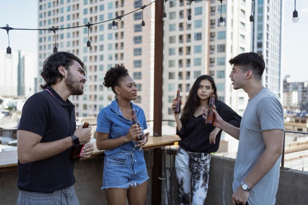 Friends socializing with bottles of beer on an urban rooftop setting.