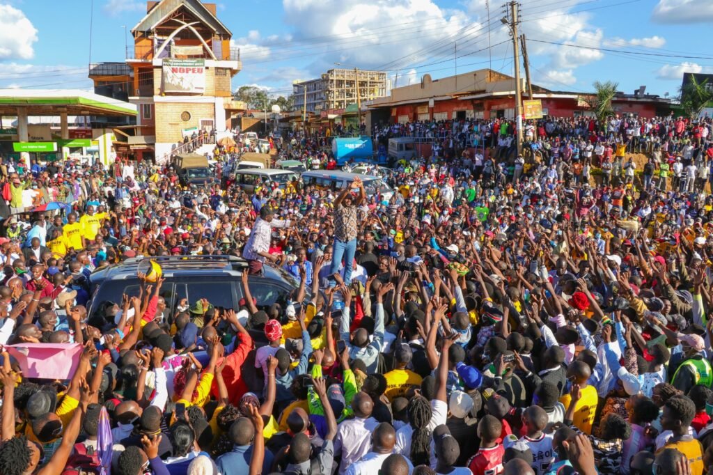 A lively outdoor event with a massive crowd and dynamic scene under a sunny sky.