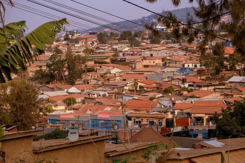 Aerial view of Kigali's suburban rooftops with lush hills in the background, showcasing vibrant community life.