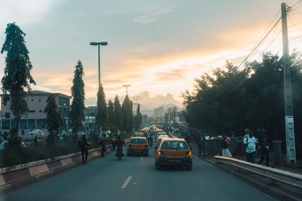 Cars and people navigating a busy city street during sunset, capturing a vibrant urban scene.