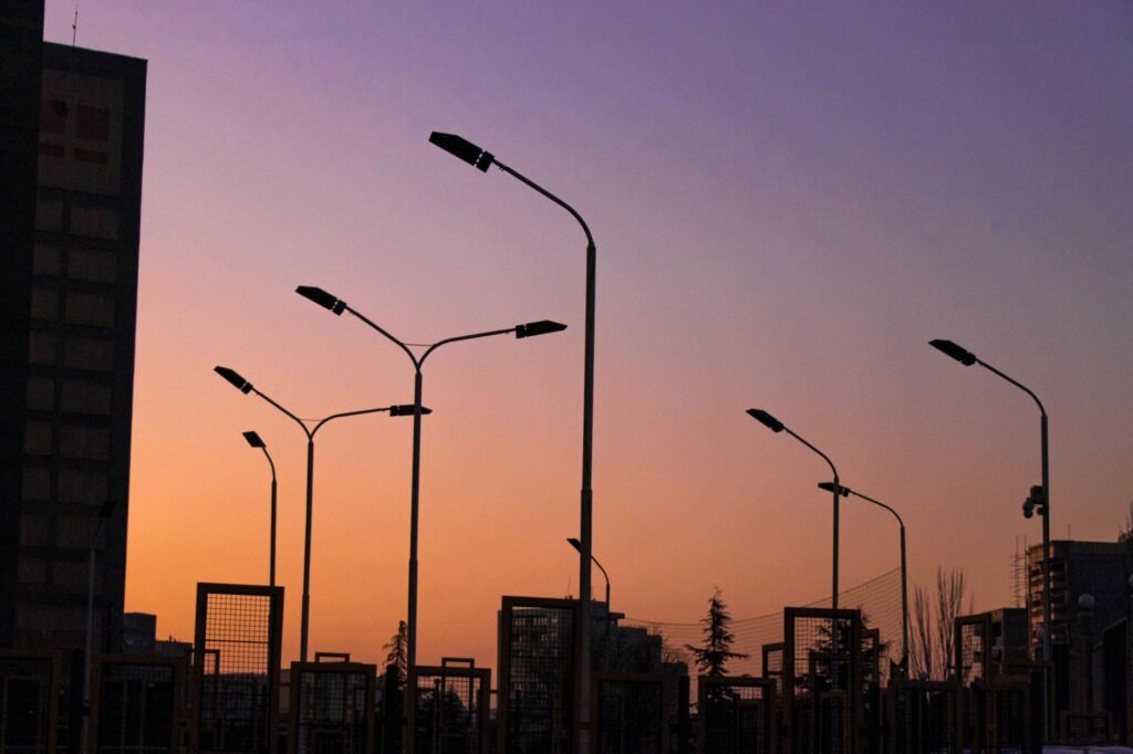 Street lamps and buildings silhouette against a vibrant twilight sky in Tabriz, Iran.