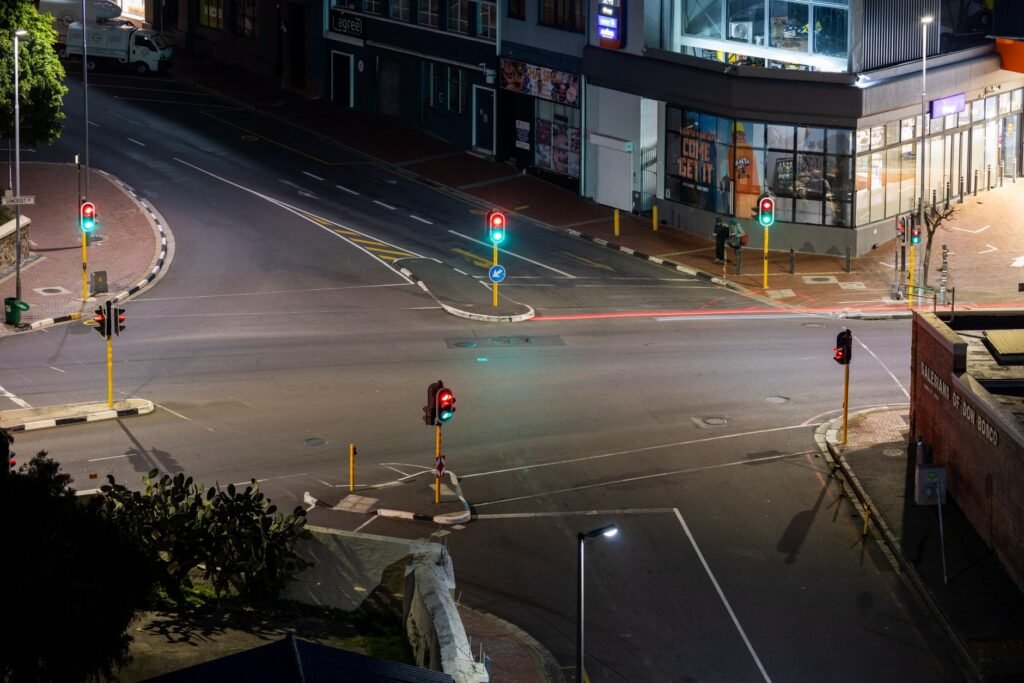 A quiet urban intersection at night with illuminated traffic lights and empty streets.