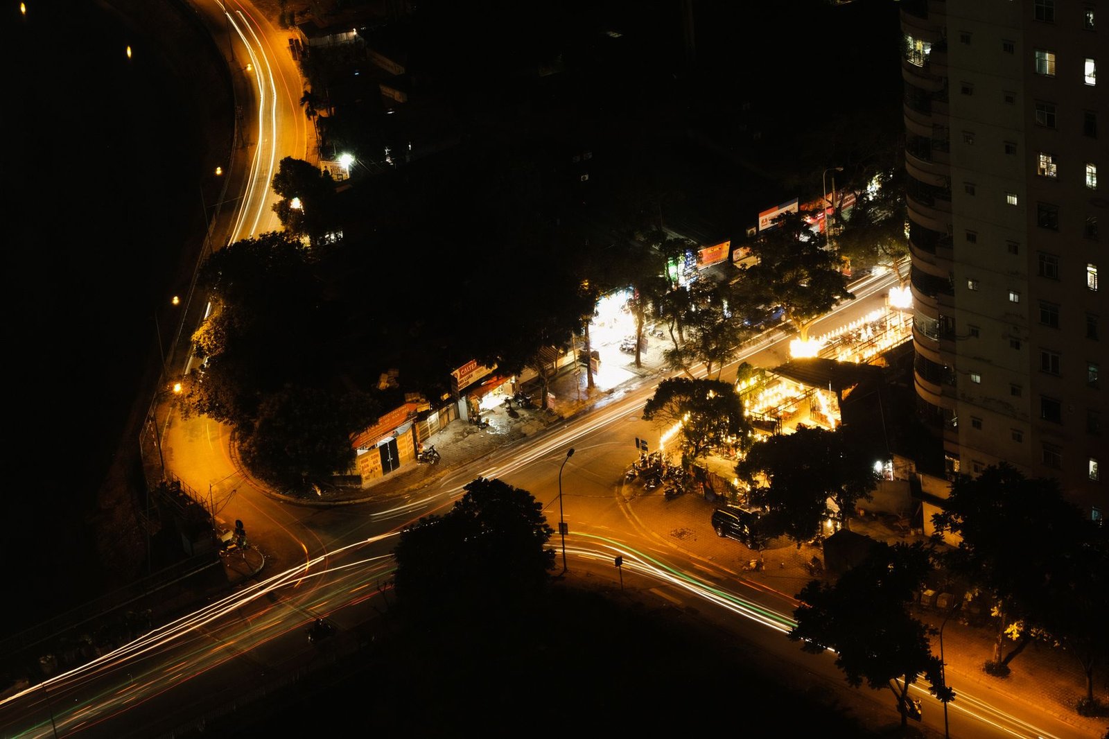 Aerial shot of city intersection at night showing light trails from vehicles.
